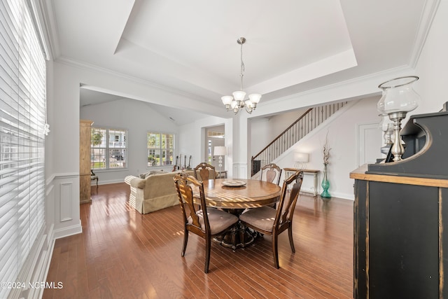 dining space featuring a raised ceiling, ornamental molding, dark hardwood / wood-style floors, and a chandelier