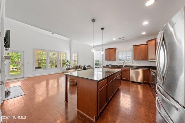 kitchen featuring stainless steel appliances, a kitchen island, sink, and dark wood-type flooring