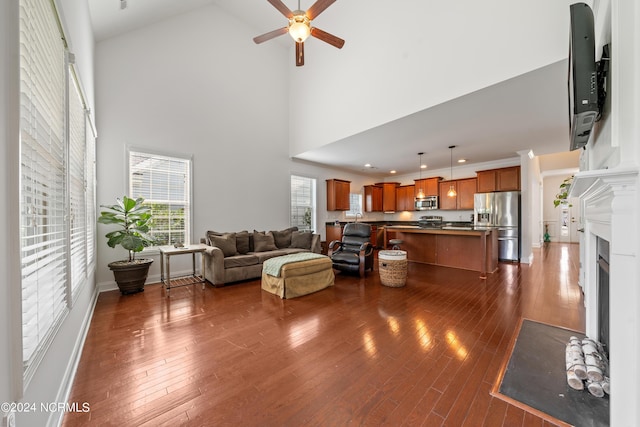 living room with a high ceiling, ceiling fan, and dark hardwood / wood-style flooring