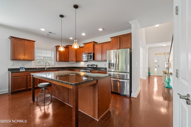 kitchen featuring pendant lighting, sink, appliances with stainless steel finishes, a center island, and dark hardwood / wood-style flooring