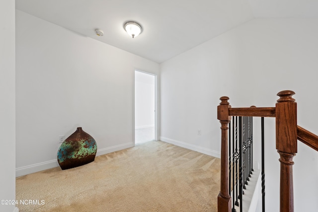 corridor with light colored carpet and lofted ceiling