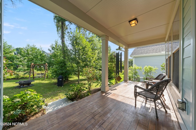 wooden terrace with a porch and a lawn