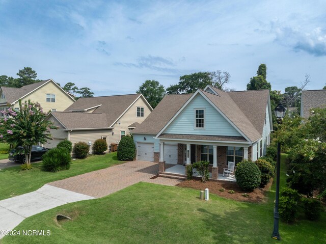 view of front of house featuring a garage, a front yard, and covered porch