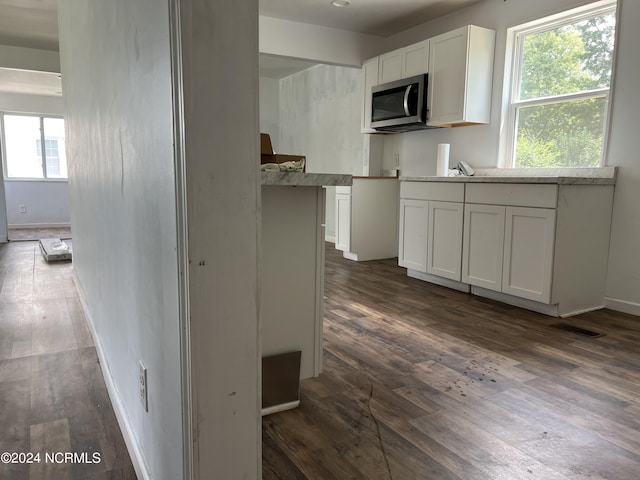 kitchen featuring dark wood-type flooring, light countertops, white cabinets, and stainless steel microwave