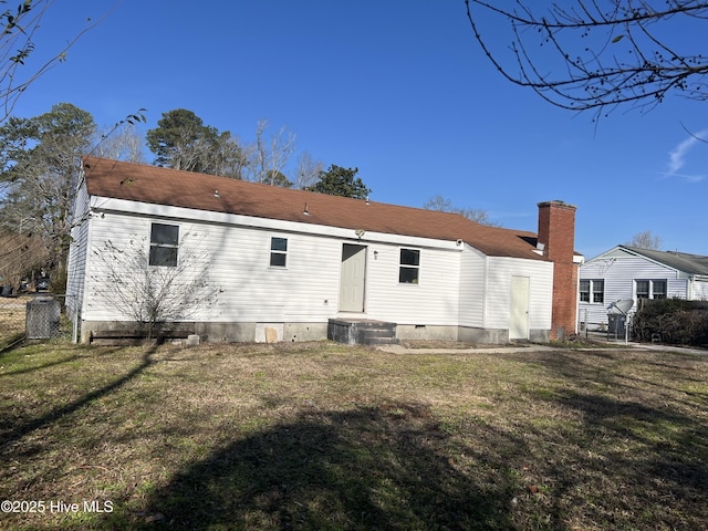 rear view of house with crawl space, fence, and a lawn