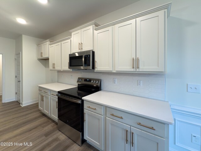 kitchen featuring appliances with stainless steel finishes, pendant lighting, white cabinetry, sink, and a kitchen island with sink