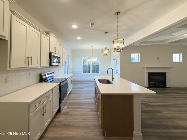 kitchen featuring sink, stainless steel appliances, an island with sink, white cabinets, and decorative light fixtures