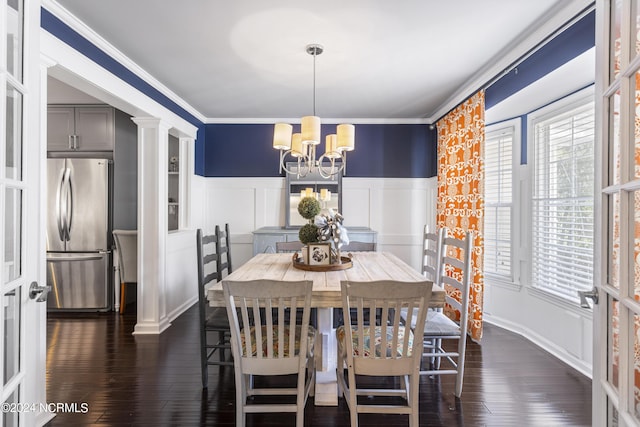 dining space featuring ornate columns, dark wood-type flooring, a notable chandelier, and ornamental molding