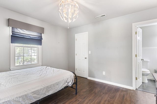 bedroom with a chandelier, ensuite bathroom, and dark wood-type flooring