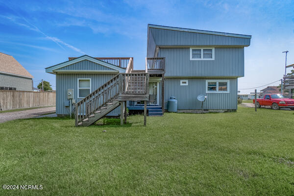 rear view of house with a wooden deck and a lawn