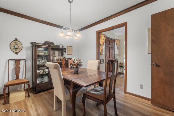 dining space featuring an inviting chandelier, wood-type flooring, and crown molding