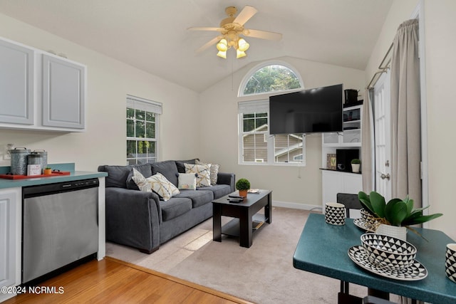 living area with lofted ceiling, ceiling fan, light wood-style flooring, and a healthy amount of sunlight