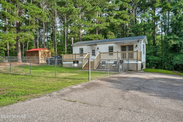 manufactured / mobile home with a deck, fence, and a front lawn