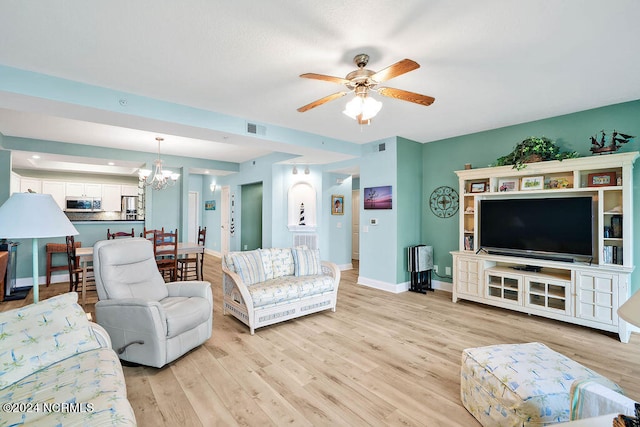 living room featuring ceiling fan with notable chandelier and light wood-type flooring