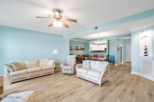 living room with ceiling fan with notable chandelier and light hardwood / wood-style floors