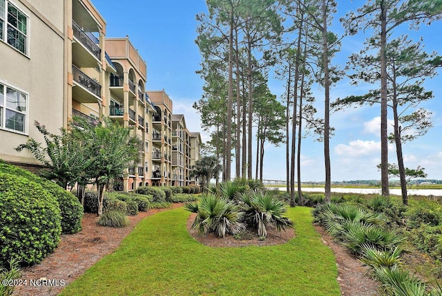 view of property's community with a water view and a lawn