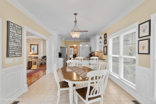 dining area with light tile patterned floors, ornamental molding, and a healthy amount of sunlight