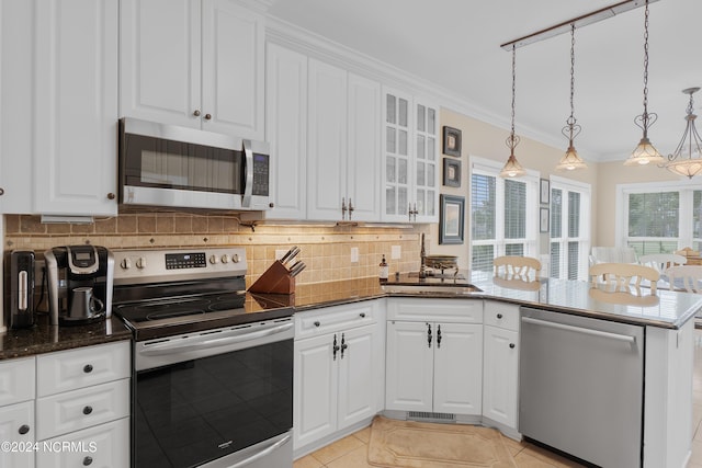 kitchen featuring decorative light fixtures, white cabinets, appliances with stainless steel finishes, ornamental molding, and glass insert cabinets