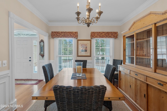 dining room featuring a wainscoted wall, light wood-style floors, crown molding, and an inviting chandelier