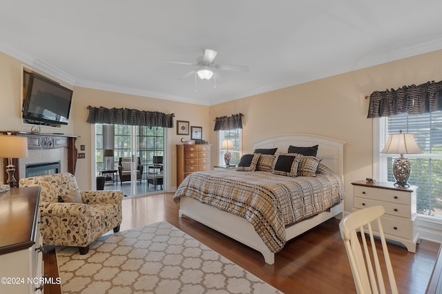 bedroom with dark wood-type flooring, a glass covered fireplace, access to outside, and crown molding