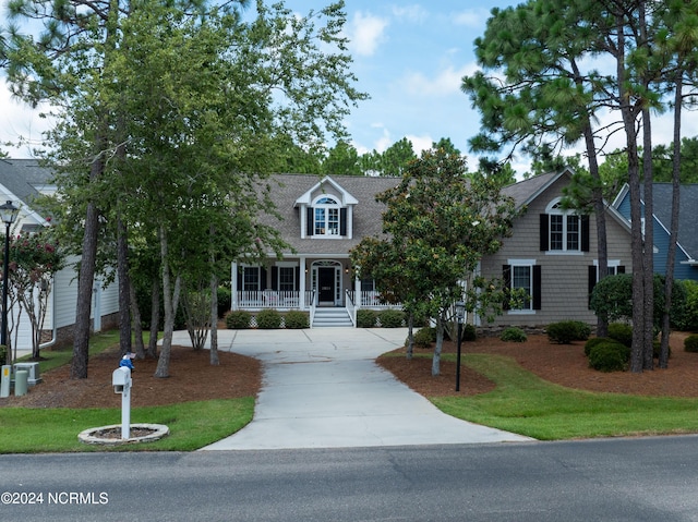 cape cod house featuring a front lawn, a porch, concrete driveway, and roof with shingles