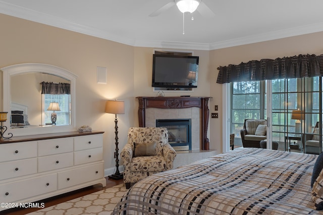 bedroom featuring baseboards, ornamental molding, a tiled fireplace, and wood finished floors