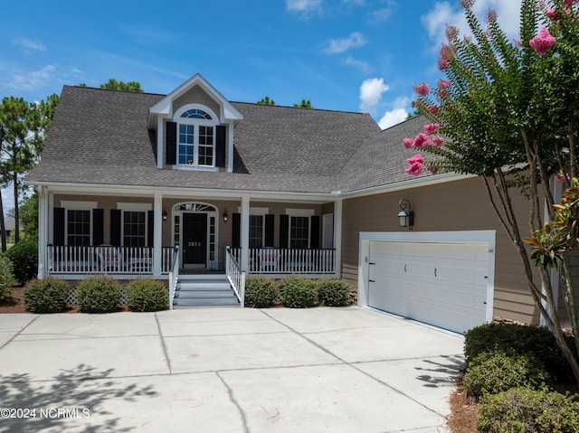 cape cod house with a garage, a shingled roof, a porch, and concrete driveway