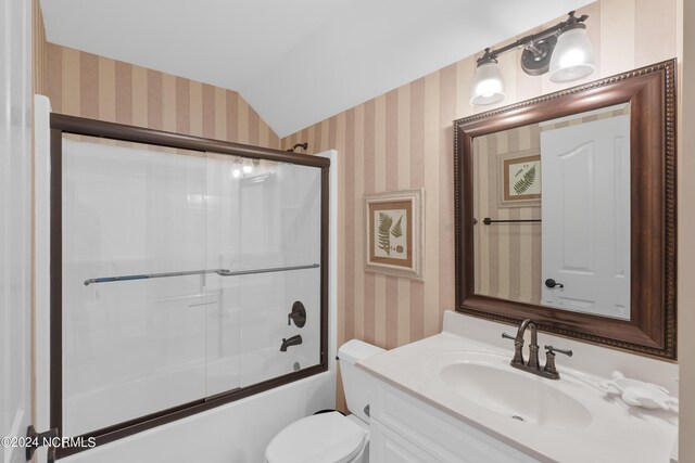 bathroom featuring shower / bath combination with glass door, lofted ceiling, toilet, vanity, and wallpapered walls