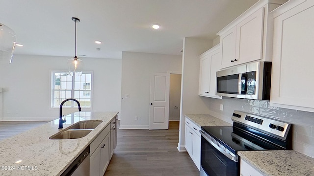 kitchen with stainless steel appliances, a sink, white cabinetry, light stone countertops, and pendant lighting