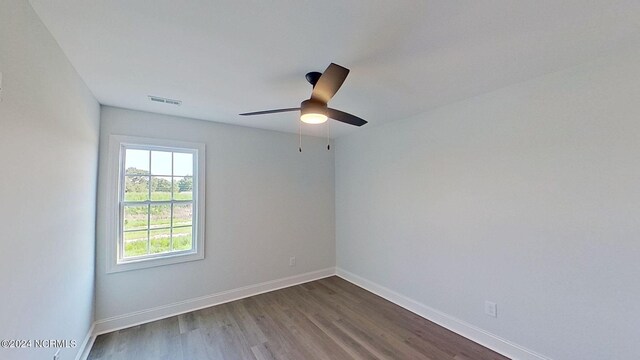 spare room with ceiling fan, dark wood-style flooring, visible vents, and baseboards