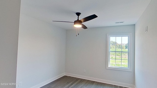 empty room with a ceiling fan, visible vents, dark wood finished floors, and baseboards