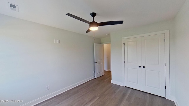 unfurnished bedroom featuring ceiling fan, wood finished floors, visible vents, baseboards, and a closet