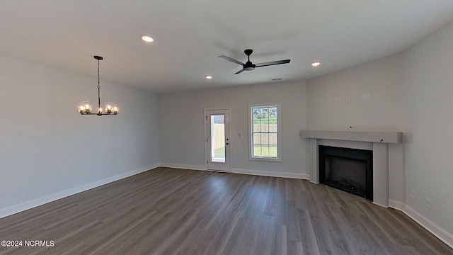 unfurnished living room with recessed lighting, ceiling fan with notable chandelier, dark wood-style flooring, a fireplace, and baseboards