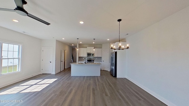 kitchen featuring white cabinets, an island with sink, appliances with stainless steel finishes, light countertops, and pendant lighting