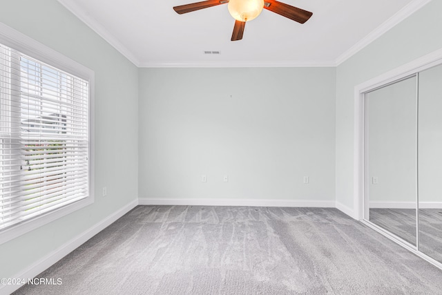 unfurnished bedroom with ceiling fan, crown molding, a closet, and carpet