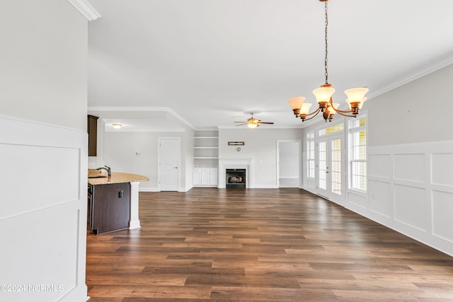 unfurnished living room with dark wood-type flooring, sink, ceiling fan with notable chandelier, and crown molding