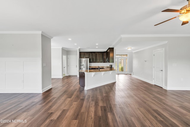 unfurnished living room featuring ceiling fan, sink, dark wood-type flooring, and crown molding