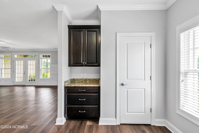 bar with dark brown cabinets, light stone counters, dark hardwood / wood-style floors, and crown molding