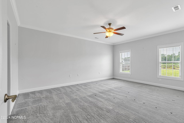 carpeted spare room with ceiling fan, ornamental molding, and plenty of natural light