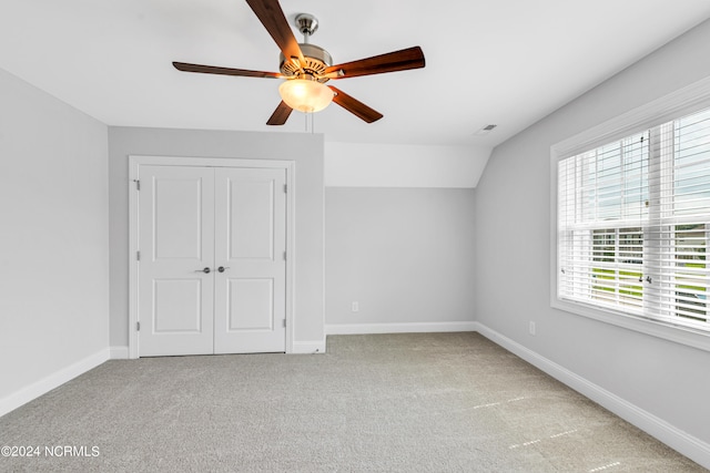 unfurnished bedroom with ceiling fan, a closet, light colored carpet, and lofted ceiling