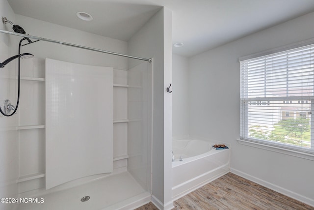 bathroom with shower with separate bathtub and wood-type flooring