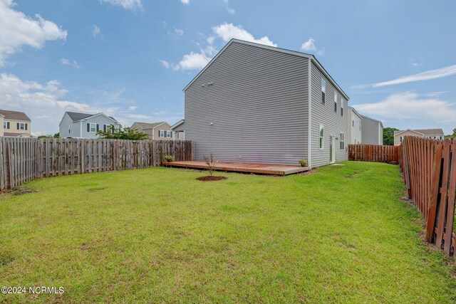 back of property with a wooden deck and a lawn