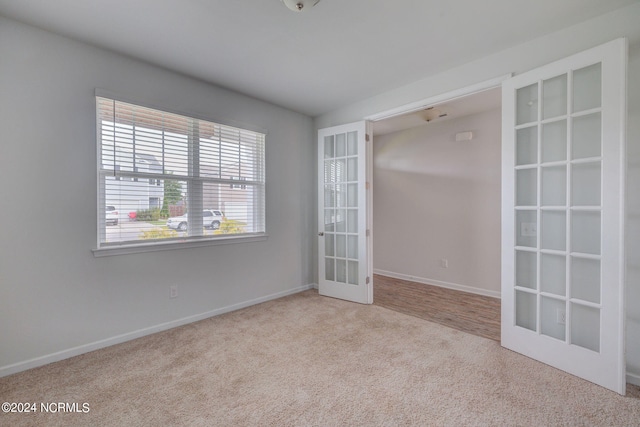 spare room featuring light colored carpet and french doors