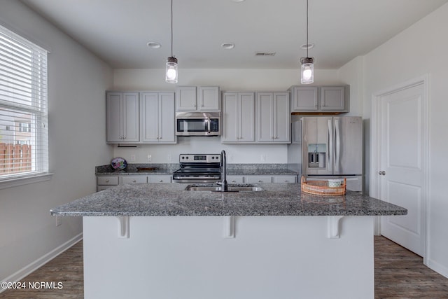 kitchen with sink, appliances with stainless steel finishes, dark hardwood / wood-style flooring, and a kitchen breakfast bar