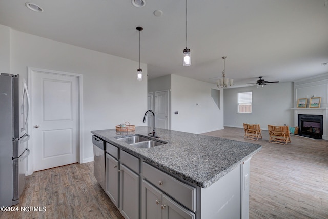 kitchen with hardwood / wood-style flooring, stainless steel appliances, sink, an island with sink, and ceiling fan