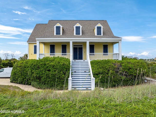 cape cod house featuring a shingled roof, stairway, and a porch