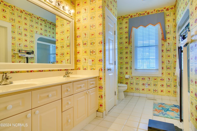 full bathroom with wallpapered walls, toilet, a sink, baseboards, and tile patterned floors