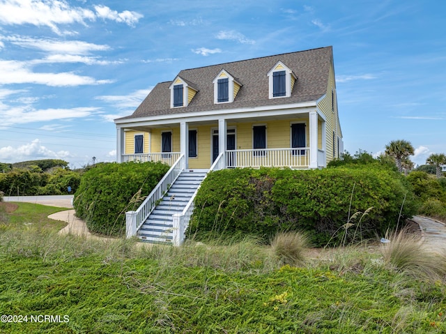 cape cod house with stairway, a porch, and roof with shingles