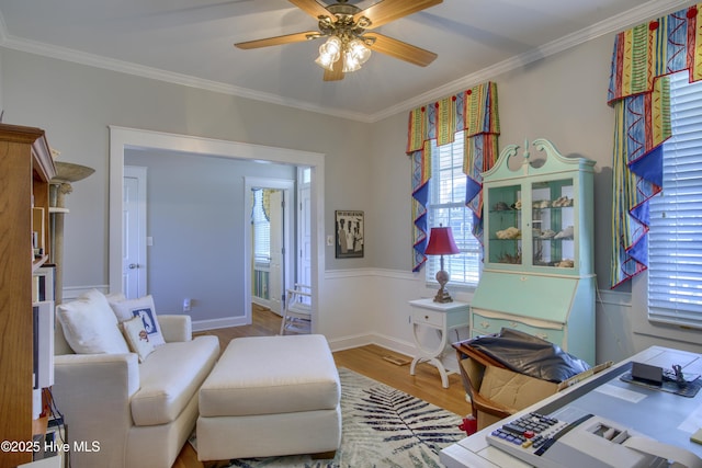 sitting room with ornamental molding, a ceiling fan, baseboards, and wood finished floors