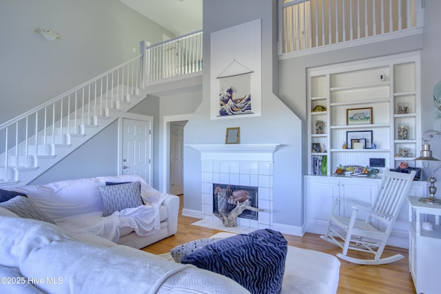 living room featuring a towering ceiling, hardwood / wood-style floors, and a tile fireplace